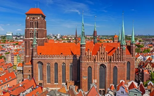 Große Backsteinkirche mit roten Dächern in der Stadt mit blauem Himmel im Hintergrund.