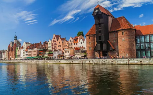 Historische Gebäude an einem Flussufer mit blauem Himmel.