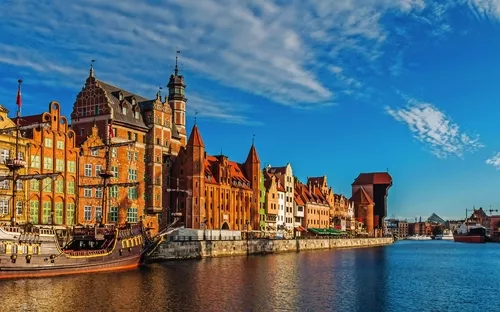 Häuserfassaden und alter Hafen bei blauem Himmel an einem Fluss.