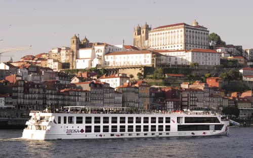 Kreuzfahrtschiff A-ROSA Alva auf dem Fluss Douro mit der Stadt Porto im Hintergrund.