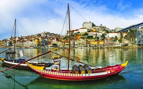 Boote auf einem Fluss mit einer Stadt im Hintergrund und einer großen Brücke links.