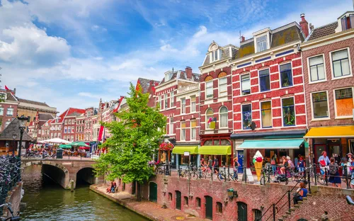 Bunte Gebäude und Menschen entlang eines Kanals an einem sonnigen Tag.