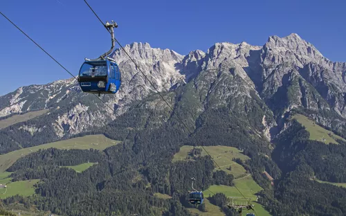 Seilbahn in alpiner Landschaft vor Bergkulisse bei klarem Himmel.