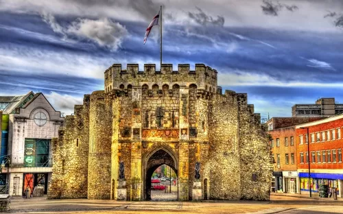 Historisches Stadttor aus Stein mit Flagge und Wolkenhimmel im Hintergrund