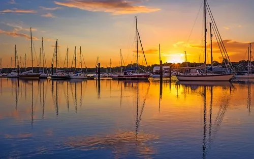 Segelboote im Hafen bei Sonnenuntergang mit Spiegelung im Wasser