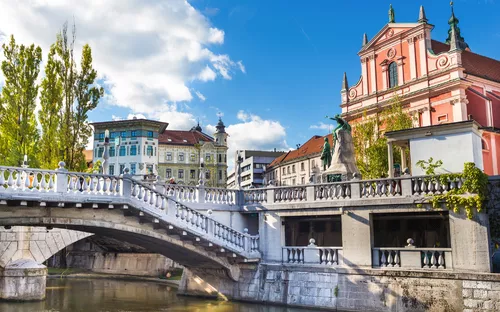 Historische Brücke und Gebäude an einem Fluss in einer Stadt bei blauem Himmel.