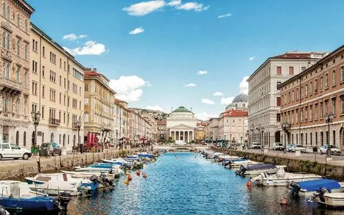 Wasserkanal in Stadt mit Booten und Gebäuden an beiden Seiten, blauer Himmel.