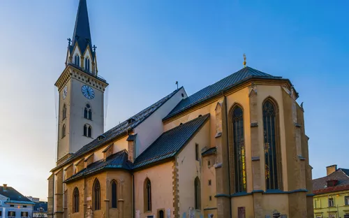 Eine große Kirche mit Turm und Uhr bei Sonnenuntergang.