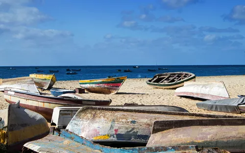 Küstenlandschaft auf der kapverdischen Insel Sal mit Fischerbooten am Strand unter blauem Himmel.