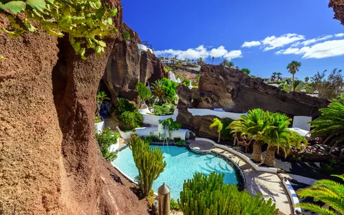 Pool in felsiger Landschaft mit Palmen und blauem Himmel