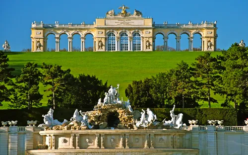 Barocke Gloriette auf Hügel mit Springbrunnen im Vordergrund.