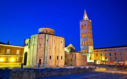 Historische Kirche und Turm bei Nacht, beleuchtet vor sternenklarem Himmel.