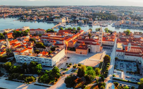 Luftaufnahme einer Küstenstadt mit historischen Gebäuden und Meeresblick.