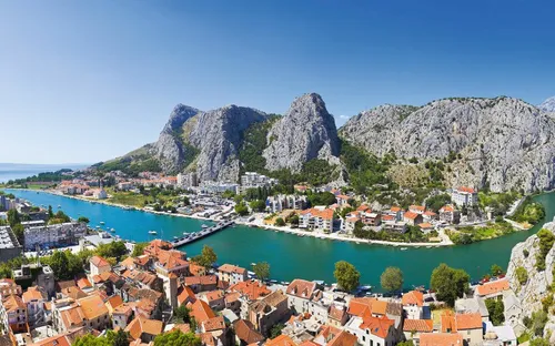 Panorama einer Stadt an einem Fluss, umgeben von Bergen.