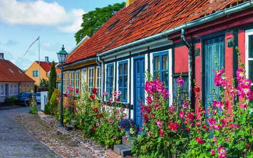 Bunte Häuser mit Blumen in einer gepflasterten Straße.