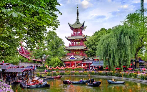 Park mit Wasserbecken, Pagode und Ruderbooten, umgeben von Bäumen und Vegetation.