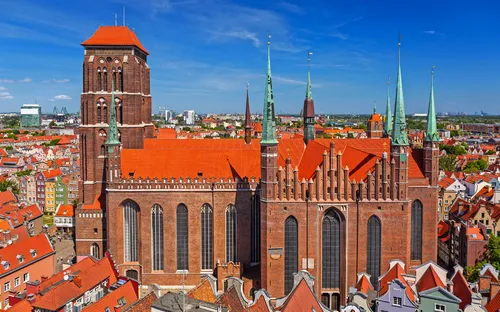 Große Backsteinkirche mit roten Dächern in der Stadt mit blauem Himmel im Hintergrund.