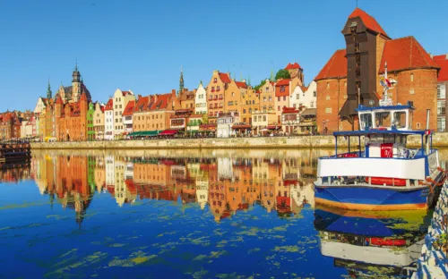 Historische Gebäude und Schiffe am Flussufer einer Stadt.