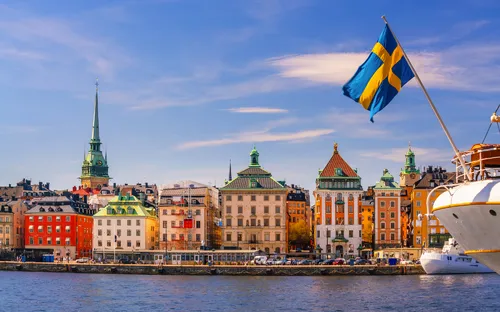 Blick auf Stockholm mit Gebäuden und schwedischer Flagge bei sonnigem Wetter.