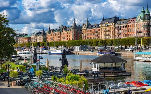Uferpromenade mit Fahrrädern, Geschäften und historischen Gebäuden am Wasser.