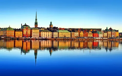 Stadtsilhouette mit reflektierenden Gebäuden am Wasser bei klarem Himmel.