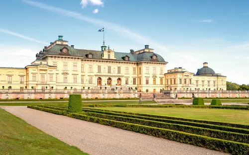 Schloss mit weitläufigem Garten und blauer Himmel im Hintergrund