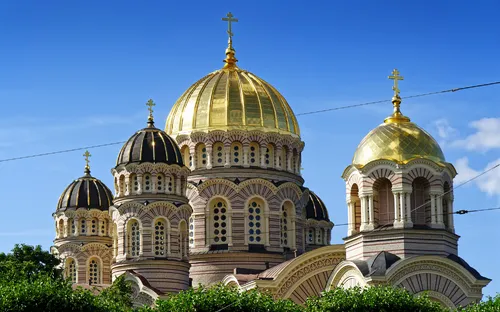 Orthodoxe Kirche mit goldenen Kuppeln und blauem Himmel im Hintergrund.