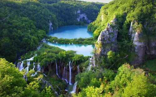 Wasserfälle und türkisfarbene Seen in einer grünen, bergigen Landschaft.