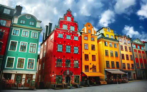 Bunte historische Gebäude an einem Platz mit blauem Himmel im Hintergrund.