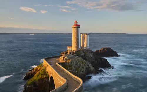 Leuchtturm auf Felsen im Meer bei Sonnenuntergang