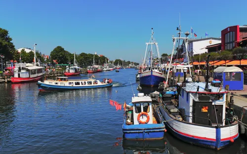 Boote in einem belebten Hafen mit blauem Himmel im Hintergrund.