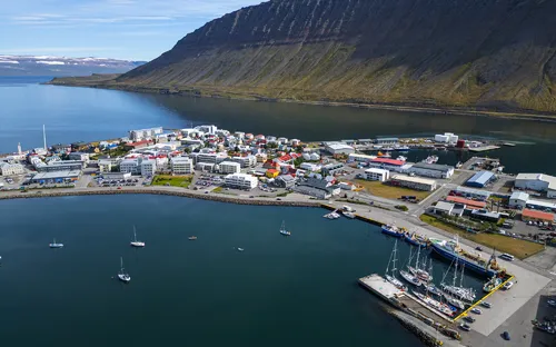 Küstenstadt mit Hafen, umgeben von Bergen und Meer.