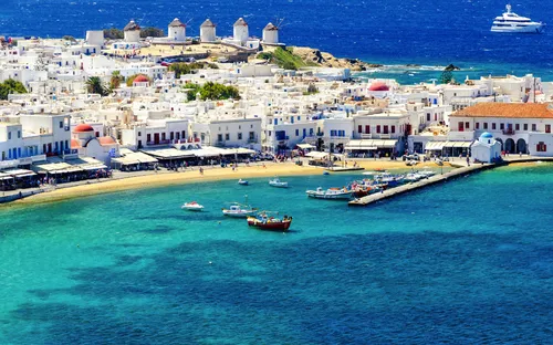 Küste mit weißen Gebäuden, Windmühlen und blauem Meer auf einer griechischen Insel.