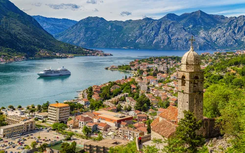 Küstenstadt Kotor mit Kreuzfahrtschiff und Bergen im Hintergrund.