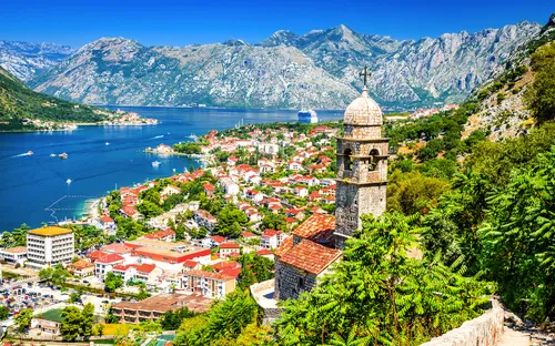 Mittelalterlicher Glockenturm mit Blick auf Küstenstadt Kotor, umgeben von Bergen und Meer.
