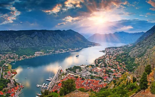 Stadt an einer Bucht mit Bergen im Hintergrund bei Sonnenuntergang.