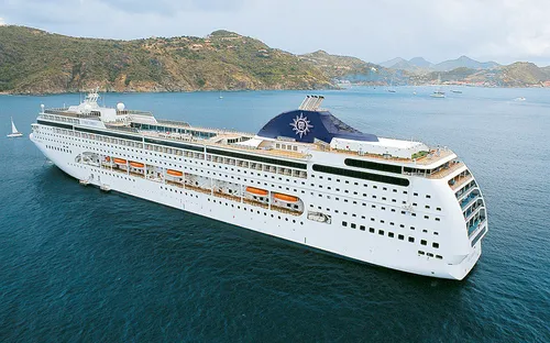 Kreuzfahrtschiff MSC Lirica auf dem Meer vor einer bergigen Küste.