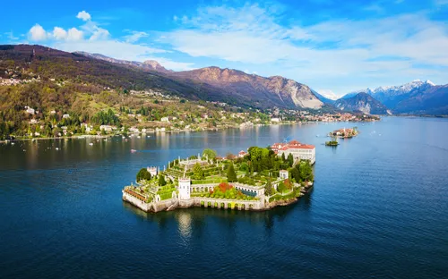 Luftaufnahme einer Insel mit historischem Gebäude in einem See umgeben von Bergen.