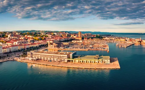 Küstenstadt mit Hafen und Gebäuden unter blauem Himmel.