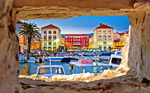 Blick auf Hafen mit Booten und historischen Gebäuden bei Abenddämmerung.