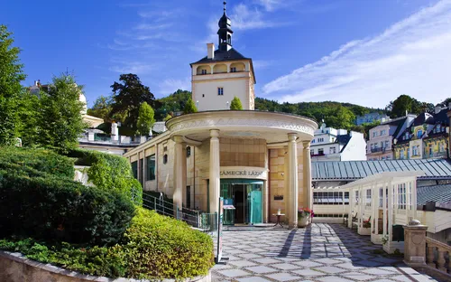 Eingangsbereich eines historischen Gebäudes mit Turm und Gartenansicht.