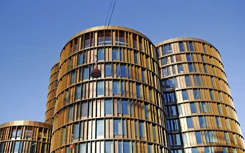 Moderne Rundgebäude mit Glasfassaden vor blauem Himmel.