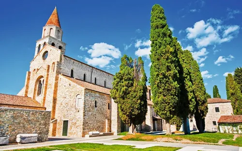 Historische Kirche mit Zypressen unter blauem Himmel.