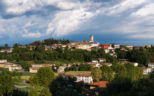 Panoramablick auf eine italienische Stadt mit Hügeln und weitem Himmel im Hintergrund.