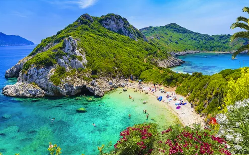 Küste mit grünem Hügel und blauem Meer im Hintergrund.