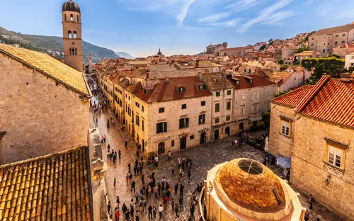 Historische Altstadt mit Menschen, weitem Himmel und alten Gebäuden.