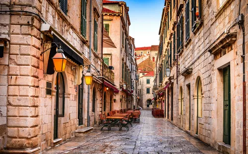 Gepflasterte Altstadtgasse mit Terrassencafé und historischen Gebäuden.