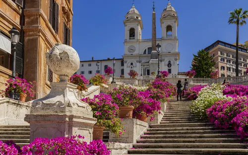Treppenstufen mit Blumen und barocker Kirche im Hintergrund an einem sonnigen Tag.