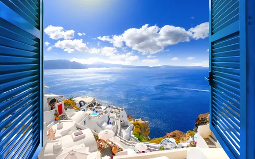 Blick aus einem Fenster auf Santorini mit weißem Dorf und blauem Meer.