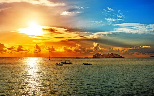 Sonnenuntergang über dem Meer mit Booten am Horizont.